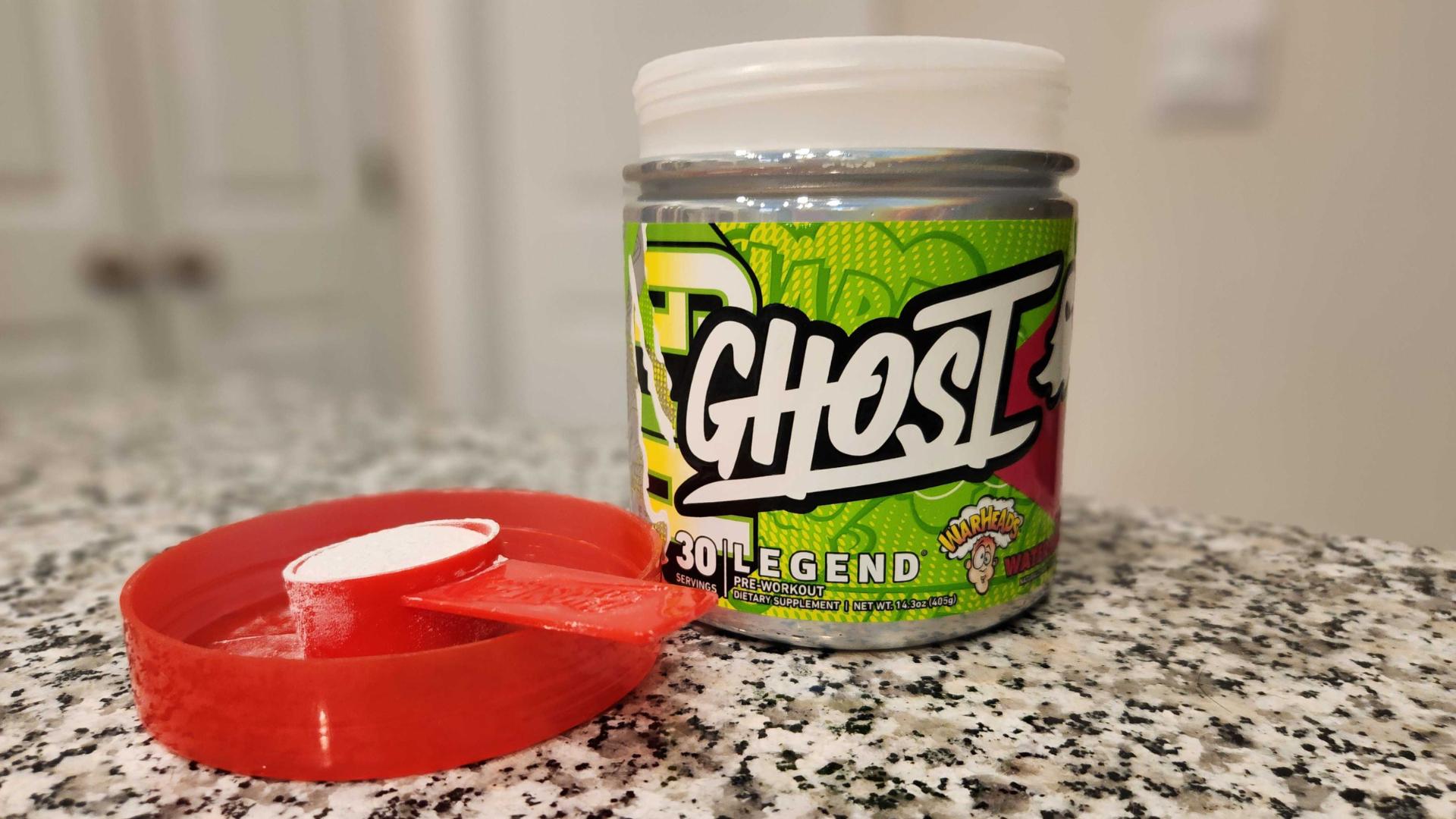 A green and red container of Ghost Legend pre-workout powder in Sour Watermelon Warhead flavor on a kitchen counter